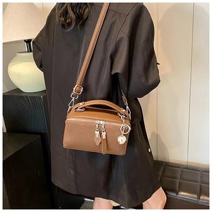 Detail view of brown pebbled leather Boston bag with silver ball charm and adjustable strap