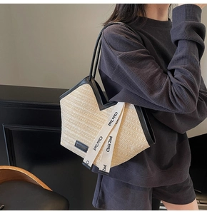 Dettaglio della borsa tote in paglia intrecciata con finiture nere e nastro decorativo