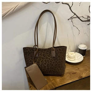 Detail shot of leopard print suede tote bag with matching pouch on a wooden table