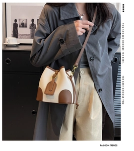Detail view of bicolor bucket bag with beige litchi texture and brown drawstring accents