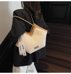 Dettaglio della borsa tote in paglia intrecciata con finiture in pelle marrone e nastro chic
