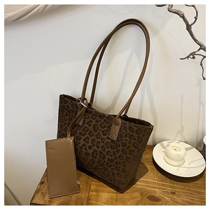 Detail of leopard print suede tote bag set with long leather handles on wood surface