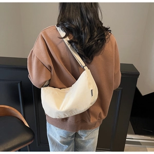 Detail of cream canvas crescent bag showing the adjustable strap and fashion label tag