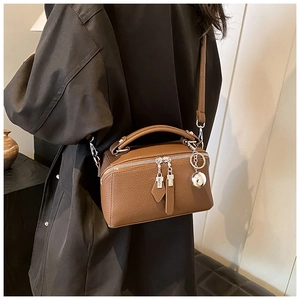 Detailed close-up of brown litchi grain leather texture and silver ball charm on handbag
