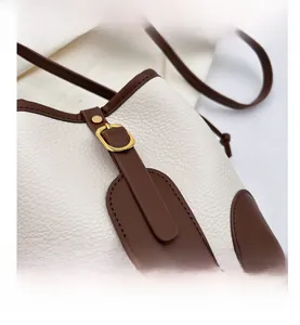 Detailed macro view of litchi grain leather texture and gold hardware on bucket bag