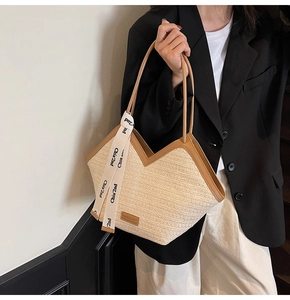 Dettaglio della borsa tote in paglia intrecciata con finiture in pelle e apertura a forma di V