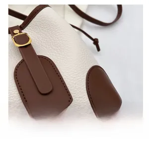 Detail of white lychee leather texture and brown trim with gold metal hardware buckle