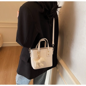 Dettaglio della mini borsa tote crema in ecopelle goffrata con ciondolo a cane