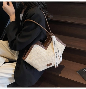 Dettaglio della borsa tote in paglia intrecciata con finiture in pelle marrone e nastro