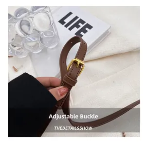 Detail view of the brown leather adjustable strap with a gold metal buckle on the bag