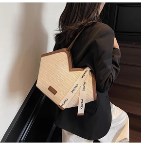 Dettaglio della borsa tote intrecciata con finiture in pelle e tracolla sulla spalla