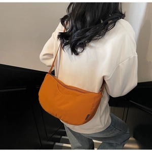 Detail view of ginger yellow crescent crossbody bag on model showing ergonomic side profile
