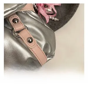 Détail d'un sac en cuir argenté avec bordure rose et rivets chromés polis et brillants