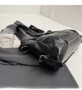 Detail of glossy black leather tote bag featuring shiny silver buckles and hardware