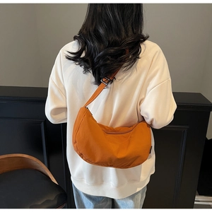 Detail view of the orange crescent shoulder bag with adjustable strap on model back