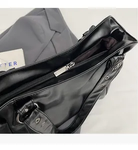 Detail shot of the smooth silver zipper closure on a black leather tote bag