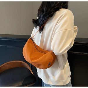 Orange crescent canvas crossbody bag with Fashion label shown on a person's back