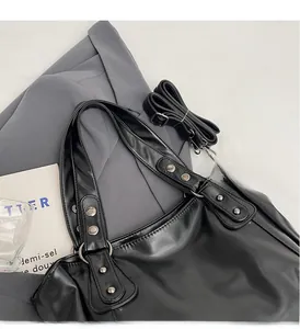 Detail of black leather tote bag featuring sturdy handles with silver rivet reinforcement