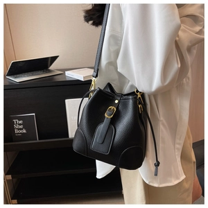 Close-up of black litchi pattern leather bucket bag with gold metal buckle detailing
