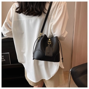 Close-up of black lychee-textured bucket bag with drawstring and gold buckle detail