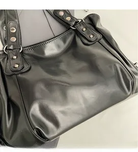 Detail of soft black leather tote bag with punk style silver metal rivets and rings