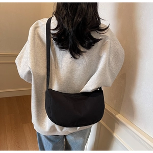 Rear view of a black crescent crossbody bag styled with a grey hoodie and casual jeans