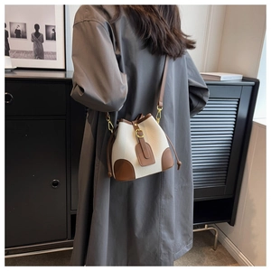 Detailed close-up of a vintage beige bucket bag featuring brown leather trim and drawstring closure