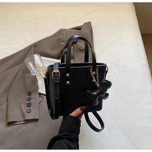 Dettaglio borsa tote nera goffrata con rivetti dorati e ciondolo a forma di orso