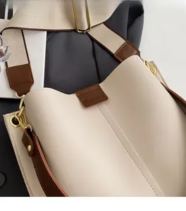 Detailed macro view of adjustable wide canvas strap and gold hardware on bucket bag