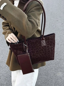 Large leopard print faux suede tote bag with matching pouch shown on woman's shoulder