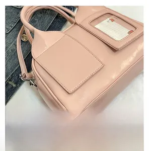 Gros plan sur le sac coquille en cuir verni rose avec fente pour carte et deux poches