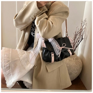 Détail d'un sac à bandoulière en cuir PU noir avec nœuds roses et bordure en dentelle