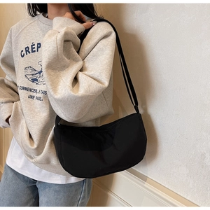 Detailed close-up of a minimalist black crescent crossbody bag worn by a model