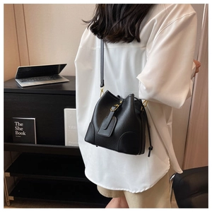 Detail of black lychee grain leather bucket bag with gold hardware and drawstring