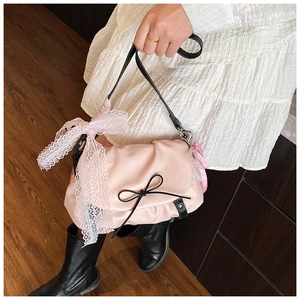 Détail du sac nuage rose avec noeud noir et breloque perle sur une robe en dentelle
