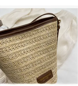 Detail showing natural woven straw texture and premium brown leather trim on the bucket bag