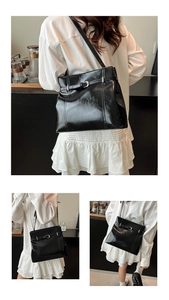 Détail du sac bandoulière en cuir noir brillant avec boucle argentée élégante