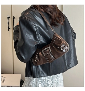 Close-up of vintage brown leather crescent bag with retro metal buckle on shoulder