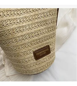 Close-up of woven straw texture and brown leather brand label on the beige bucket bag