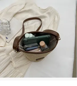 Interior view showing straw bucket bag capacity with phone, tablet and cosmetics inside