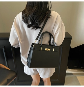 Rear view of model wearing a black leather handbag with gold hardware and strap