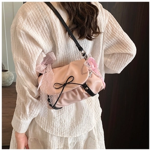 Détail du sac nuage rose montrant la dentelle, le nœud et le pendentif cœur perlé