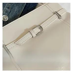 Gros plan détaillé d'un sac seau en cuir crème montrant la boucle argentée et les coutures