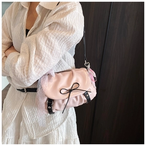 Détail du sac plissé rose avec nœud noir et ruban en dentelle accessoirisé