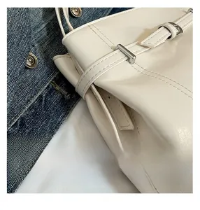 Gros plan sur le sac seau blanc brillant avec boucle métallique argentée et surpiqûres
