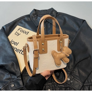 Dettaglio mini borsa tote con goffratura a stella e ciondolo a cane su pelle nera