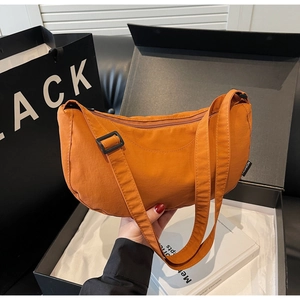 Close-up of orange nylon crescent bag showing textured fabric and fashion side label