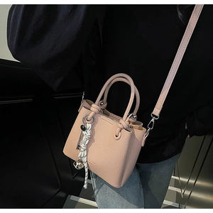 Détail d'un sac seau rose à grain de litchi avec foulard imprimé et charm clochette