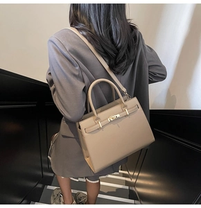 Close-up of structured light brown leather handbag with metallic clasp and adjustable strap