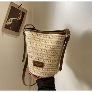 Summer straw bucket bag with brown leather trim and adjustable shoulder strap for beach